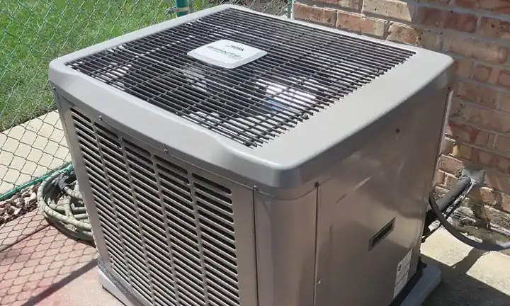 Central air conditioner condenser unit outside a brick home